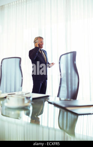 Uomo in sala conferenze a parlare sul suo telefono cellulare Foto Stock