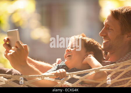 Padre e Figlio con tavoletta digitale in amaca Foto Stock