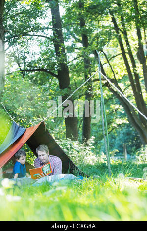 Padre e figlio della lettura in tenda da campeggio Foto Stock