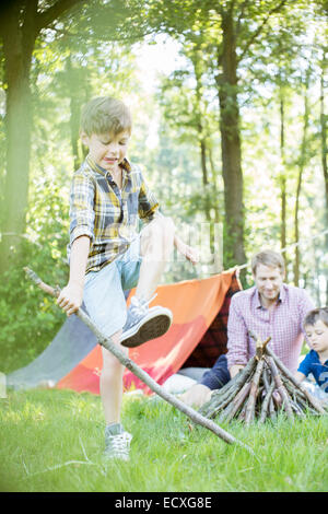 Ragazzo stick di rottura per il falò con padre e fratello Foto Stock