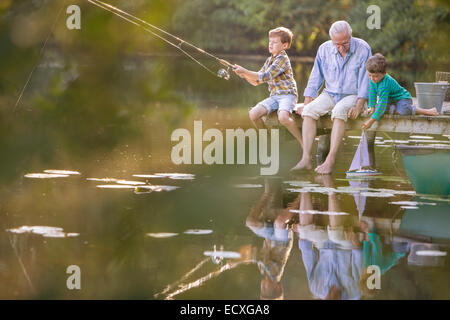 Nonno e nipoti la pesca e giocare con il giocattolo in barca a vela sul lago Foto Stock