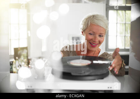 Donna anziana la riproduzione di dischi in vinile sul giradischi Foto Stock