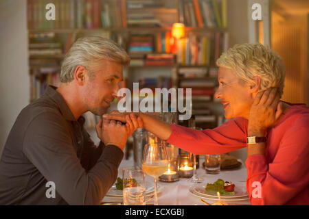 Uomo più anziano di baciare la mano della moglie a cena romantica Foto Stock