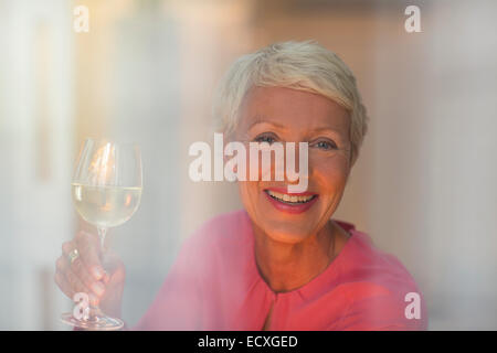 Donna anziana di bere un bicchiere di vino bianco Foto Stock