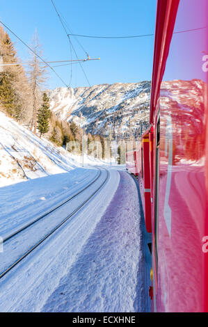 Bernina Express noto anche come il trenino rosso è una ferrovia che uniscono l'Italia e la Svizzera attraverso Alpi lungo un sentiero innevato Foto Stock