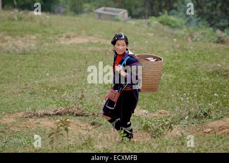 Una donna Hmong che porta i suoi prodotti sulla strada per il mercato a Sapa Foto Stock