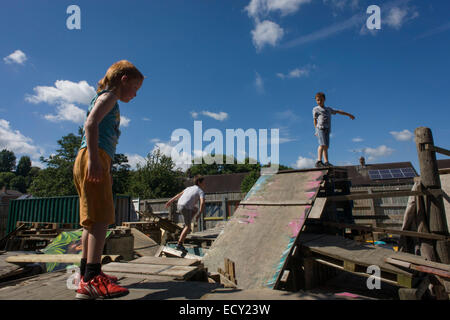 I bambini giocano su vecchie casse e pallet in avversione al rischio parco giochi chiamato terra su Plas Madoc station wagon, Ruabon, Wrexham, Galles. Foto Stock