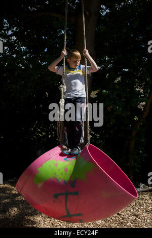 Ragazzo altalene sulla corda in avversione al rischio parco giochi chiamato terra su Plas Madoc station wagon, Ruabon, Wrexham, Galles. Foto Stock