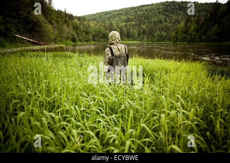 Mari uomo in wading stivali in piedi di alte erbe palustri Foto Stock