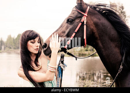 La donna caucasica petting cavallo all'aperto Foto Stock