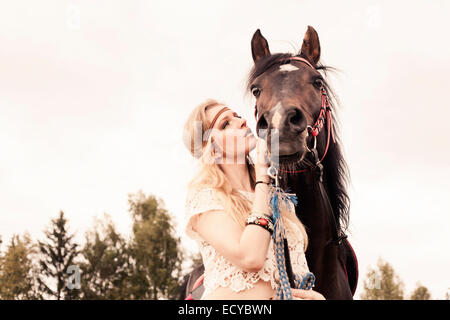 La donna caucasica petting cavallo all'aperto Foto Stock