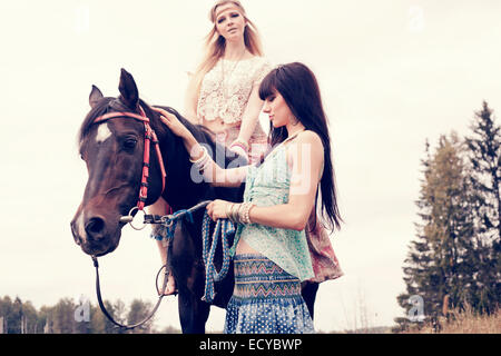 Donne caucasici petting e equitazione all'aperto Foto Stock