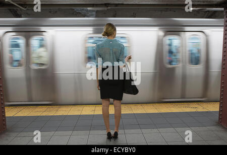 Caucasian woman standing passando vicino alla metropolitana in una stazione ferroviaria Foto Stock