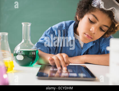 Razza mista boy utilizzando digitale compressa in aula nel laboratorio di scienze Foto Stock