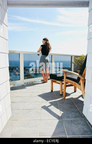 Razza mista donna ammirando vista panoramica dal balcone Foto Stock