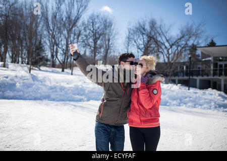 Coppia caucasica tenendo cellulare selfie in inverno Foto Stock