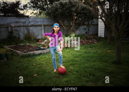 Razza mista ragazza che gioca con la palla calcio in cortile Foto Stock