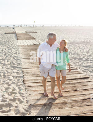 Coppia caucasica camminando sulla passerella in legno sulla spiaggia Foto Stock