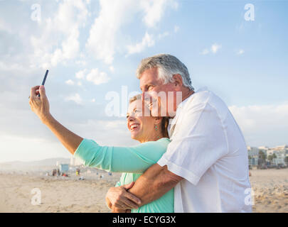 Coppia caucasica tenendo cellulare selfie sulla spiaggia Foto Stock