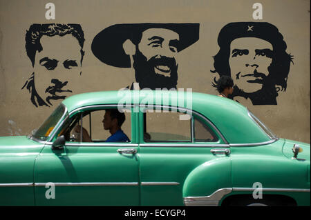 L'Avana, Cuba - Giugno 13, 2011: Classic American car drives passato stencil billboard dotate di Mella, Cienfuego e Guevara. Foto Stock