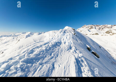 Paese indietro piste da sci al vertice con una vista maestosa dell'arco alpino in un paesaggio invernale. Cielo blu chiaro. Il Piemonte, Italia Foto Stock