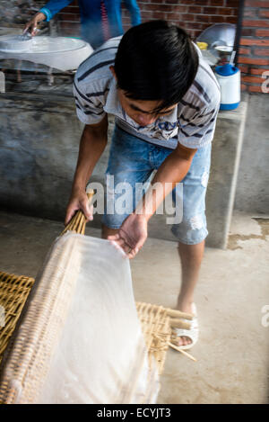 Famiglia vietnamita che lavorano nel loro piccolo home fabbrica di carta di riso e spaghetti di riso e la loro essiccazione su rack di bambù. Foto Stock