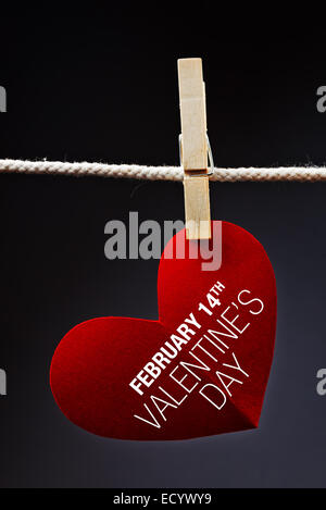 A forma di cuore il giorno di San Valentino card con messaggio attaccato ad una corda con perni di vestiti. Il romanticismo, di amore e di affetto del concetto. Foto Stock