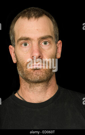 Ritratto di un robusto brizzolato uomo di mezza età con t-shirt nera su sfondo nero Foto Stock