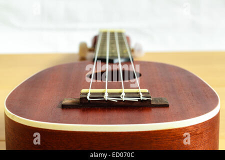 Un ukulele su uno sfondo di legno , piccola chitarra Foto Stock