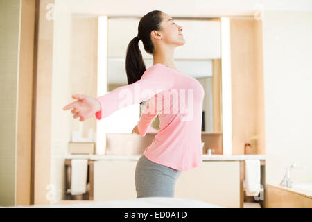 Giovane donna stretching in camera da letto Foto Stock