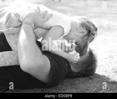 Padre giacente sull'erba che gioca con sua figlia Foto Stock