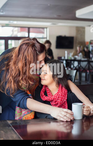 Madre baciare figlia (6-7) sul fronte in cafe Foto Stock