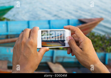 L'uomo prendendo foto di barche su un lago, lago Phewa, Pokhara, Nepal Foto Stock