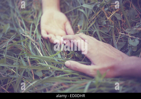 Uomo e donna che si stendono in erba tenendo le mani Foto Stock