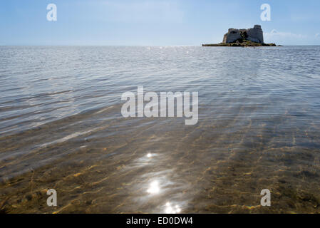 In Spagna, in Catalogna, Tarragona, Alfacs Bay, vista ravvicinata di calma mare poco profondo con le rovine di Sant Joan Tower a distanza Foto Stock