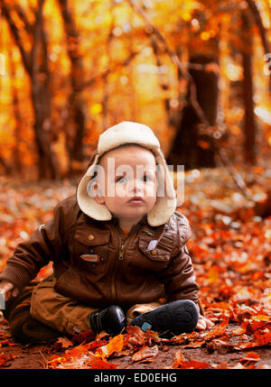 Little Boy (6-11 mesi) seduti nelle foglie in posizione di parcheggio Foto Stock