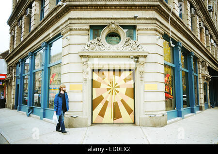 Un uomo cammina per le strade di New York City, Manhattan di fronte ad un edificio con un sacco di fotocamere e una porta dell'anca tenendo un sacco. Foto Stock