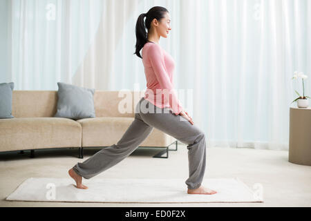 Giovane donna a praticare yoga in salotto Foto Stock