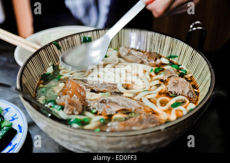 Si mangia una ciotola di noodle tradizionali di manzo taiwanese Foto Stock