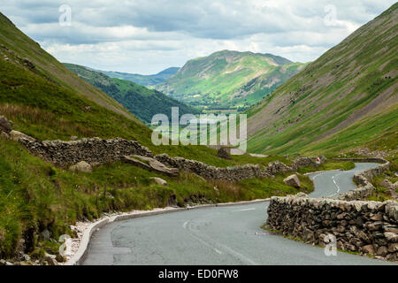 Regno Unito, Inghilterra, Cumbria, Lake District, strada tortuosa e muro di pietra lungo montagne Foto Stock