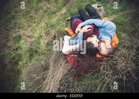 Coppia giovane sdraiato sull'erba e abbracciando Foto Stock