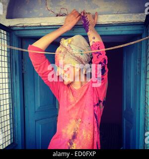 Giovane donna con velo e faccia dipinta appoggiata contro lo sportello blu Foto Stock