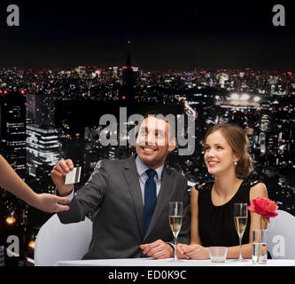Coppia sorridente pagando per la cena con carta di credito Foto Stock