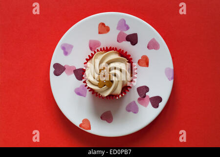 Tesco Merry Christmas Gingerbread tortina con una salsa di nascosto centro sul cuore isolato di piastra su sfondo rosso - guardando verso il basso a partire da sopra Foto Stock