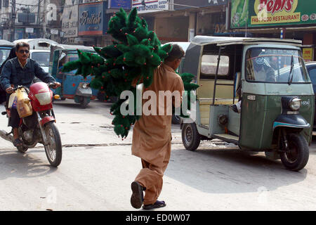 Venditore ambulante vende decorazione di Natale di elementi a guadagnare il suo sostentamento per supporta la sua famiglia alla strada prima del giorno di Natale in area Saddar a Karachi il Martedì, Dicembre 23, 2014. Foto Stock