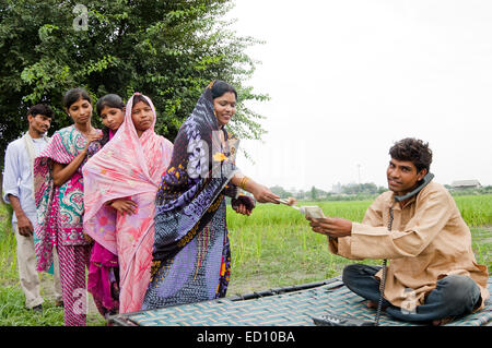1 rurale indiano agricoltore parlando di telefono di lavoro e dare i soldi Foto Stock