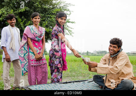1 rurale indiano agricoltore parlando di telefono di lavoro e dare i soldi Foto Stock