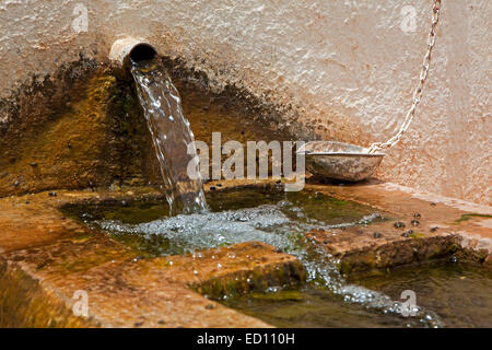 Con acqua fresca di montagna da ben versando nella vecchia fontana con lavabo in pietra di offrire acqua potabile alle persone e animali domestici Foto Stock