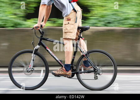 Un ciclista viaggia lungo una strada a Londra, Inghilterra Foto Stock