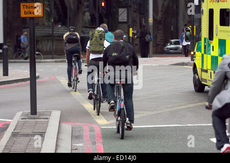 I ciclisti in sella lungo una strada a Waterloo, Londra, accanto a un'ambulanza e "pensare moto' segno. Foto Stock